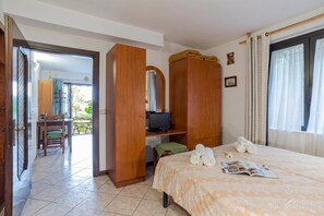 A hotel room with a bed, a television, a desk, and a chair.