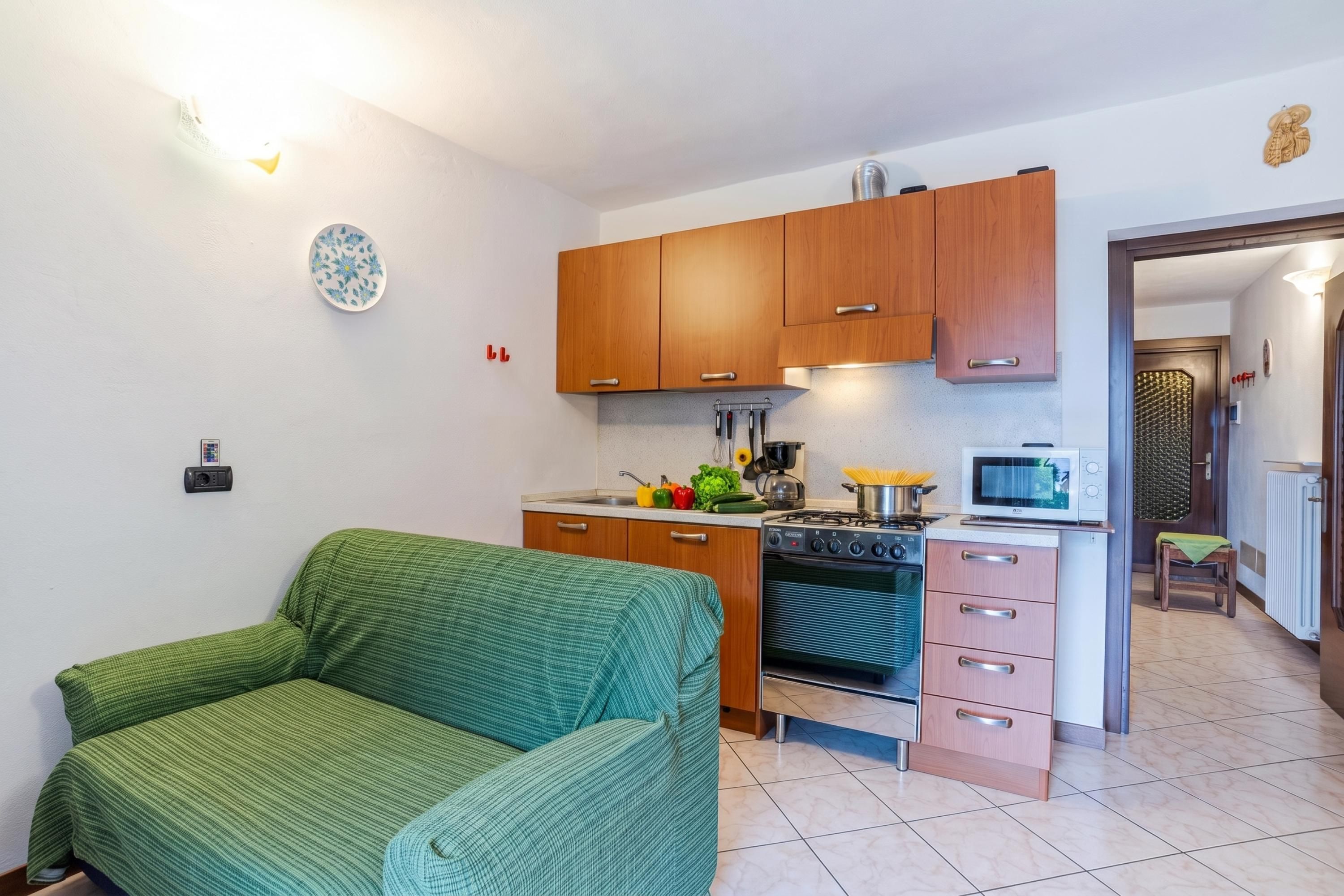 Un espacio habitable compacto con kitchenette, un sofá y una zona de comedor.