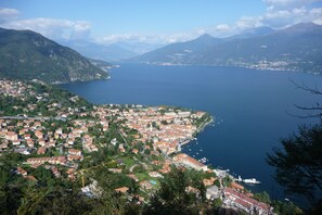 A coastal town with a dense cluster of buildings, a marina with boats, and a mountainous backdrop. - Co.ri. Appartamenti Dependance (Menaggio)