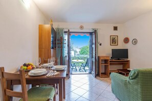 A dining area with a table set for two, a television, and a sofa. - Co.ri. Appartamenti Dependance (Menaggio)