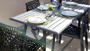 An outdoor dining area with a table set for four, chairs, and a view of the ocean. - L'échappée Belle en Tout Compris (Linguizzetta)