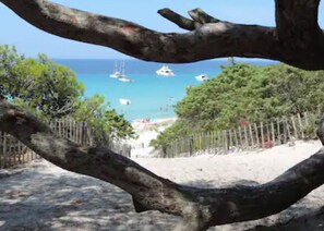 A beach with boats in the water, a wooden fence, and trees. - L'échappée Belle en Tout Compris (Linguizzetta)