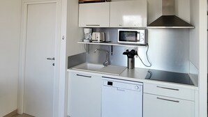 A compact kitchen with white cabinets, a microwave, a coffee maker, and a dishwasher. - L'échappée Belle en Tout Compris (Linguizzetta)