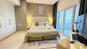 A modern bedroom with a large bed, bedside lamps, a nightstand, a window with a view, and a small table with a candle. - Manzil - Cozy Studio nr Downtown w Canal Views (Dubai)
