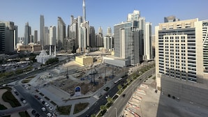 A cityscape with modern high-rise buildings, a prominent tower, and a construction site. - Manzil - Cozy Studio nr Downtown w Canal Views (Dubai)