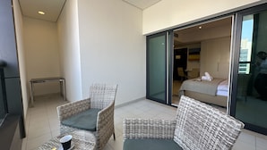 A balcony with wicker furniture, a small table, and a chair. - Manzil - Cozy Studio nr Downtown w Canal Views (Dubai)