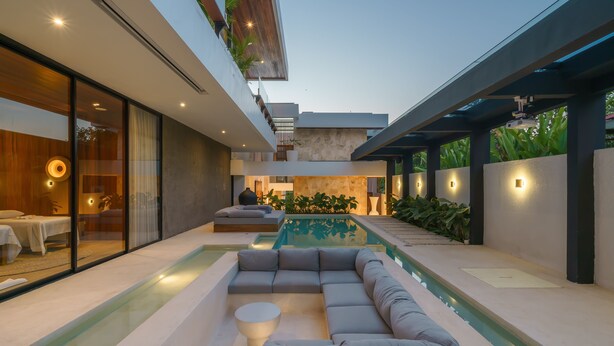 Uma área moderna com piscina ao ar livre, espaço para sentar integrado e escadaria que leva a um andar superior.