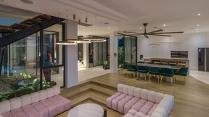 Uma sala de estar ampla com cozinha moderna, área de refeições e escadaria para um andar superior.