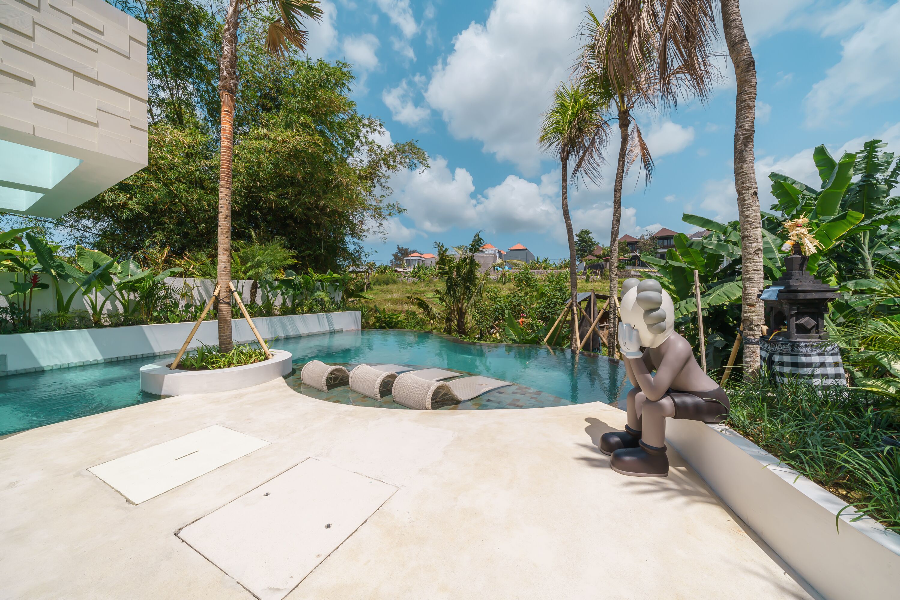 A swimming pool with a modern design, surrounded by palm trees and tropical plants.