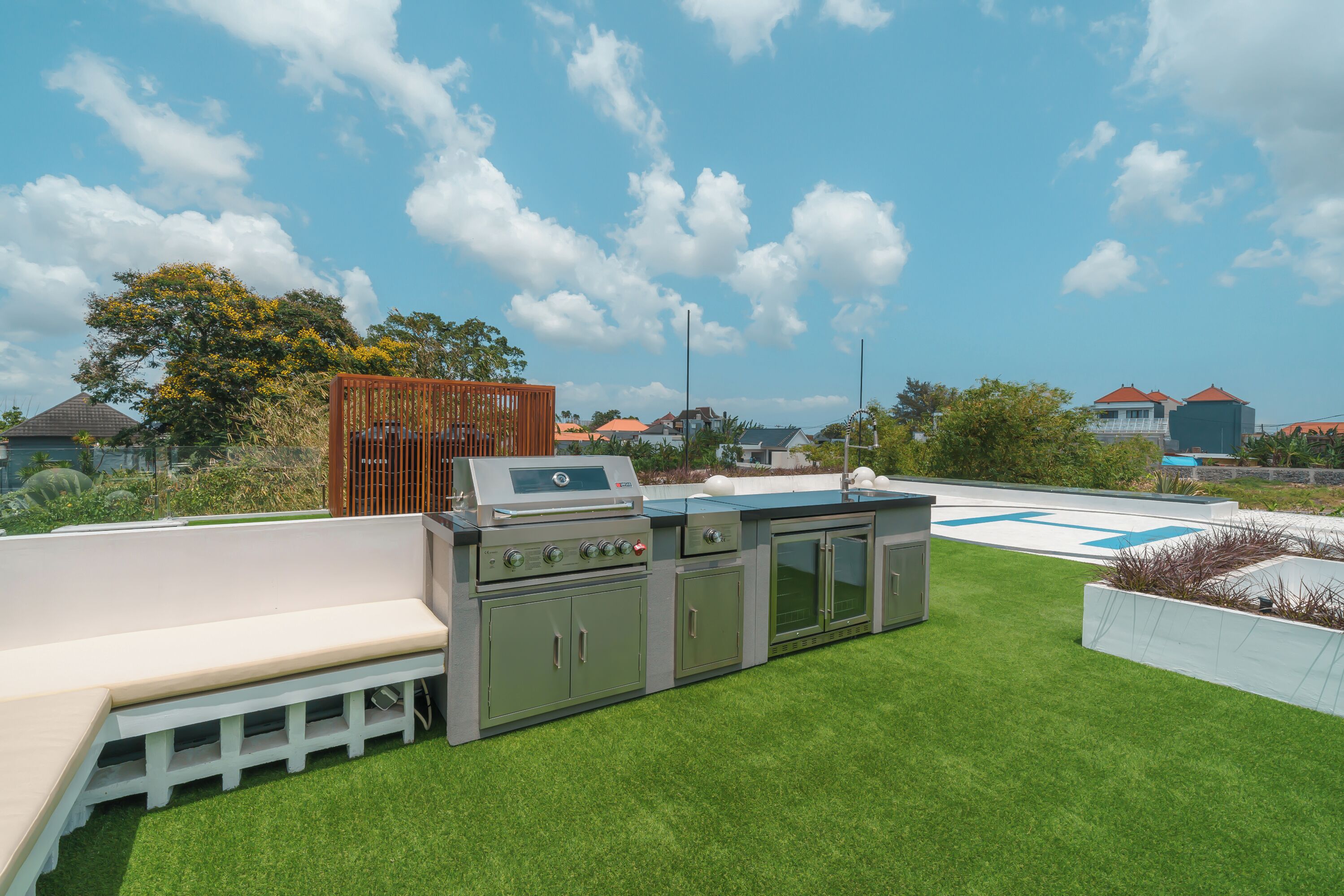 A rooftop with a barbecue grill, a seating area, and a pool.