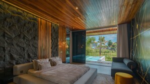 Quarto moderno com uma cama grande, um sofá e vista para uma piscina e jardim.