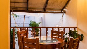A round wooden table with chairs in a covered outdoor area with a view of a garden. - Room-hb4 Double Room With Private Bathro (Cartagena)