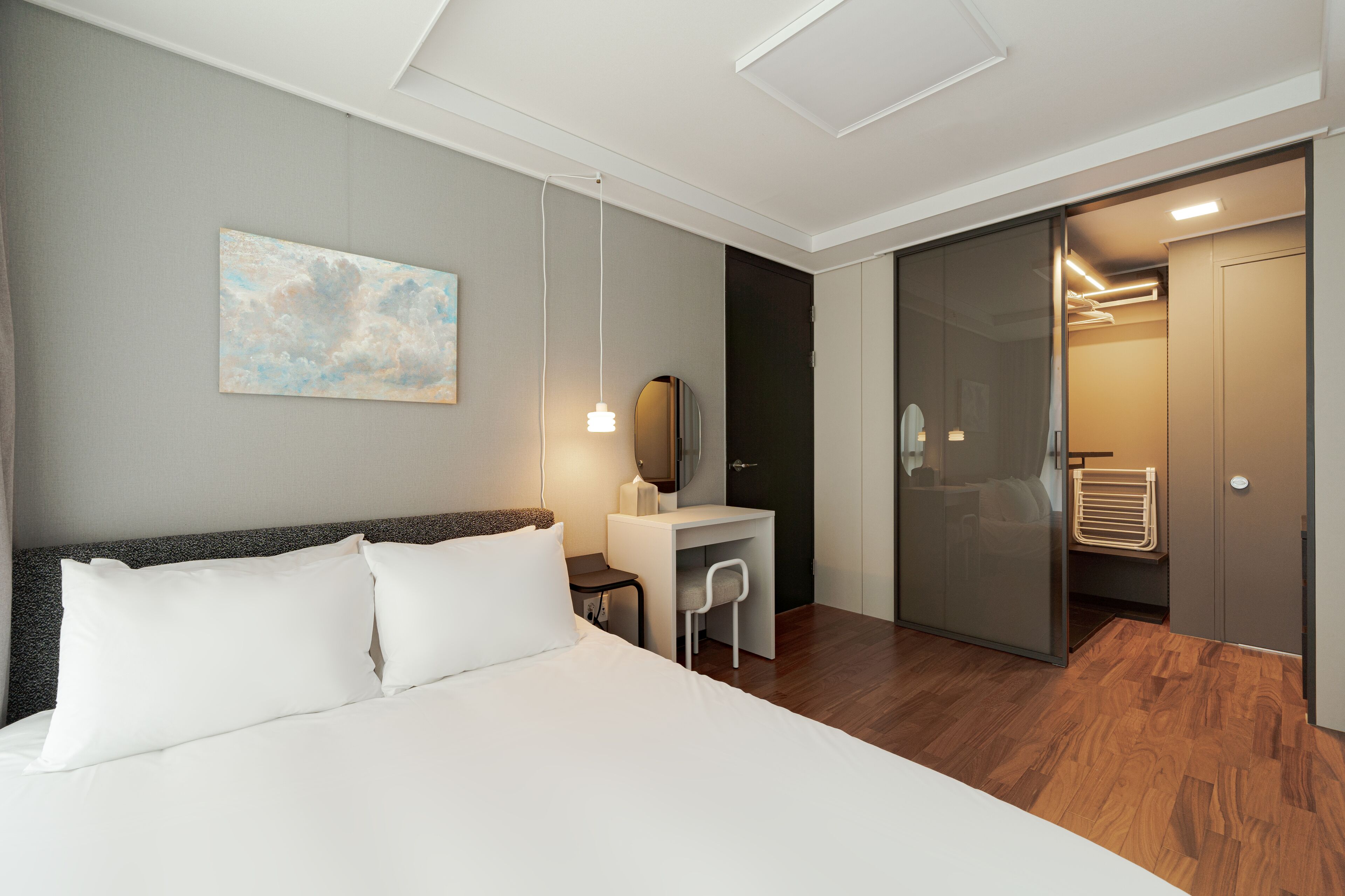 A modern hotel room with a bed, desk, and a walk-in closet.