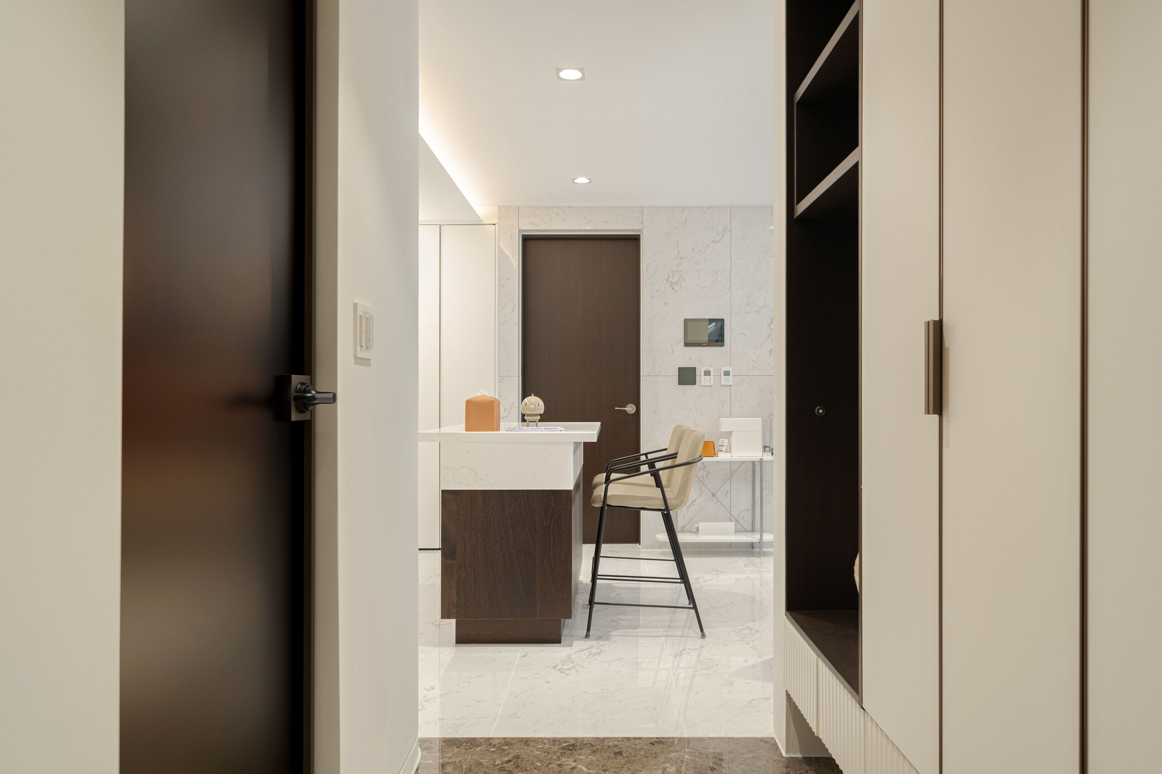Une cuisine moderne avec un plan de travail en marbre, une porte en bois foncé et un tabouret de bar.