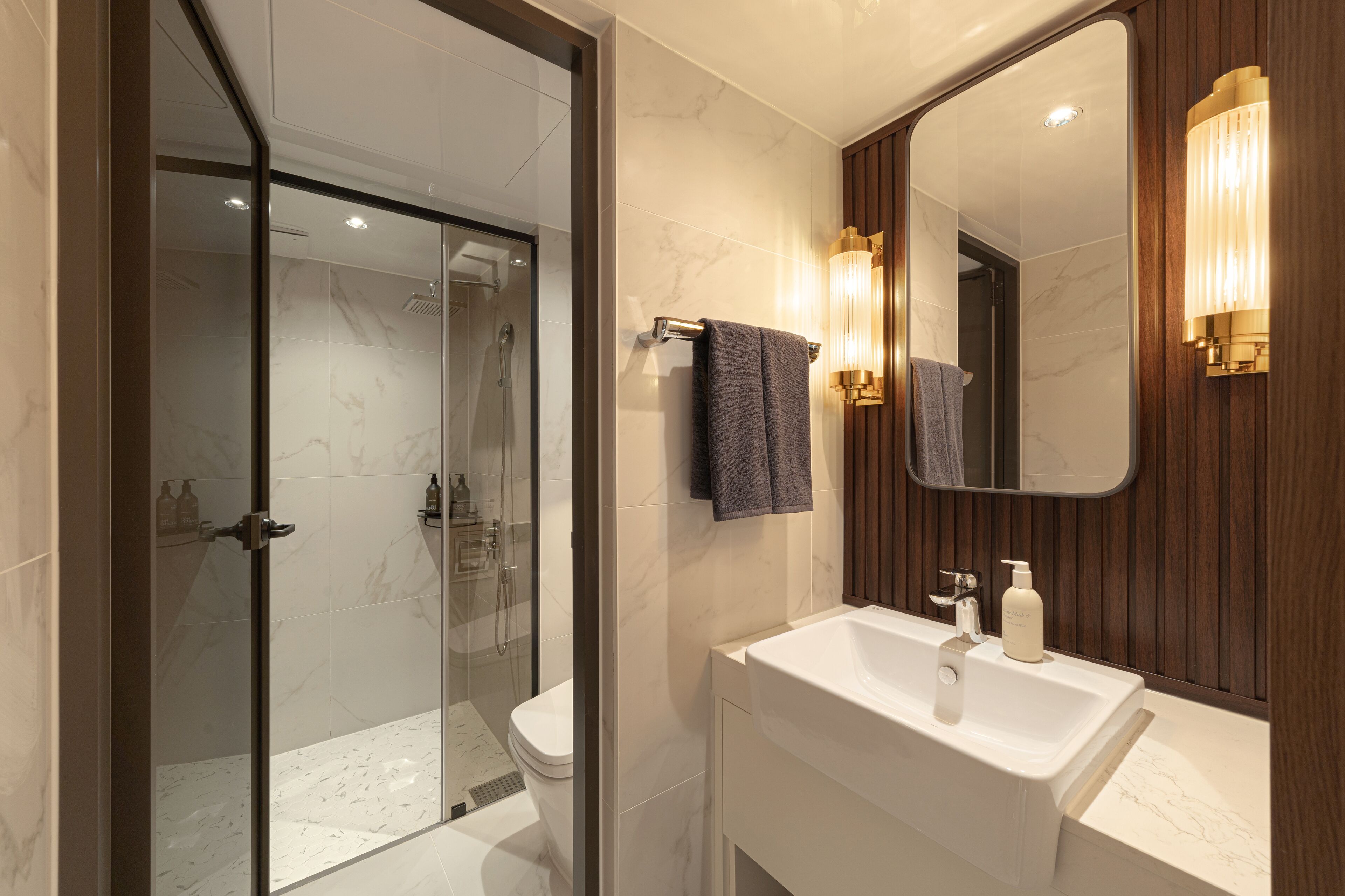 A modern bathroom with a glass-enclosed shower, a white sink, and a wooden vanity.