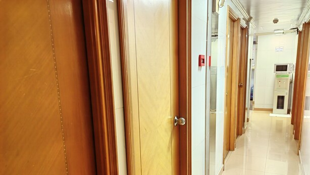 Un couloir d’hôtel avec des portes en bois et un sol carrelé.