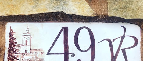 A house number sign with a simple illustration of a building and trees.