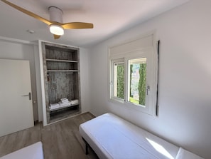 A room with a bed, a wardrobe, a ceiling fan, and a window with a view.
