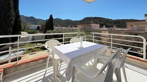 Una terraza con una mesa y sillas, con vistas a un paisaje montañoso.