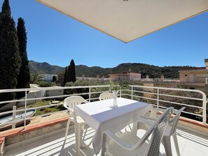 A terrace with a table and chairs, overlooking a mountainous landscape.