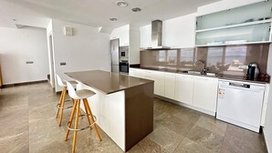 A modern kitchen with a central island, white cabinetry, stainless steel appliances, and a dishwasher. - Agi Turo Villa 1 Casa for rent in Roses Girona. (Roses)