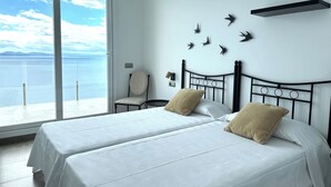 A bedroom with two beds, a chair, and a wall-mounted shelf. - Agi Turo Villa 1 Casa for rent in Roses Girona. (Roses)