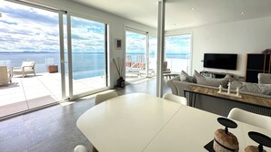A modern living room with a large white table, striped sofas, and a TV. - Agi Turo Villa 1 Casa for rent in Roses Girona. (Roses)