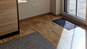 A modern room with a wooden wall feature, a large window, and a door. - Place2be - Your feel-good apartment, Ankommen und wohlfühlen! (Calden)