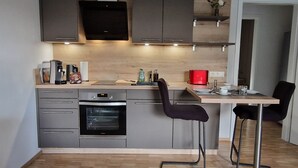 A compact kitchen with a built-in oven, a coffee maker, and a red toaster. - Place2be - Your feel-good apartment, Ankommen und wohlfühlen! (Calden)