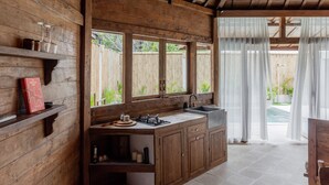 Un interior de madera con una zona de cocina, que incluye armarios, un lavamanos y un ventilador de techo.