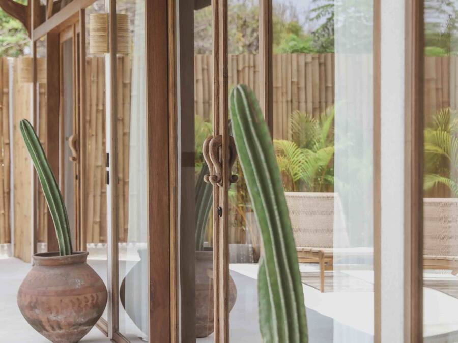 A covered outdoor area with wooden beams and glass doors, featuring two large terracotta pots with cacti.