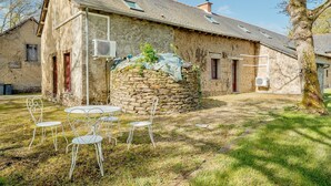A rustic stone building with a sloped roof, a small garden with metal chairs, and a tree in the foreground. - Holiday Home 'Maison De Campagne SPA, Rennes Parc Expo' with Jacuzzi, Private Garden & Wi-Fi (Mordelles)