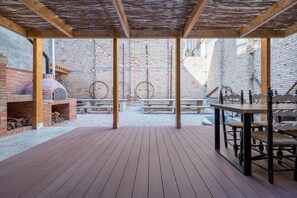 Un patio al aire libre con un horno de ladrillo, mesas y bancos de madera.