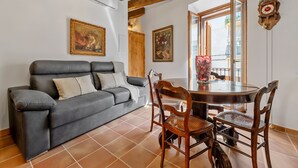 Un salon avec un canapé gris, une table à manger en bois, des chaises et deux tableaux accrochés au mur.