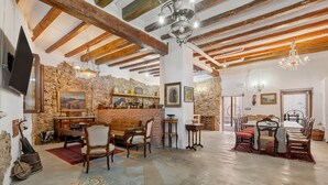 Un intérieur rustique avec des poutres apparentes, un mur en pierre, un coin bar et un espace repas.
