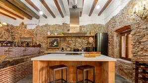 Une cuisine dotée d’un grand îlot central, de murs en pierre et d’une esthétique rustique.