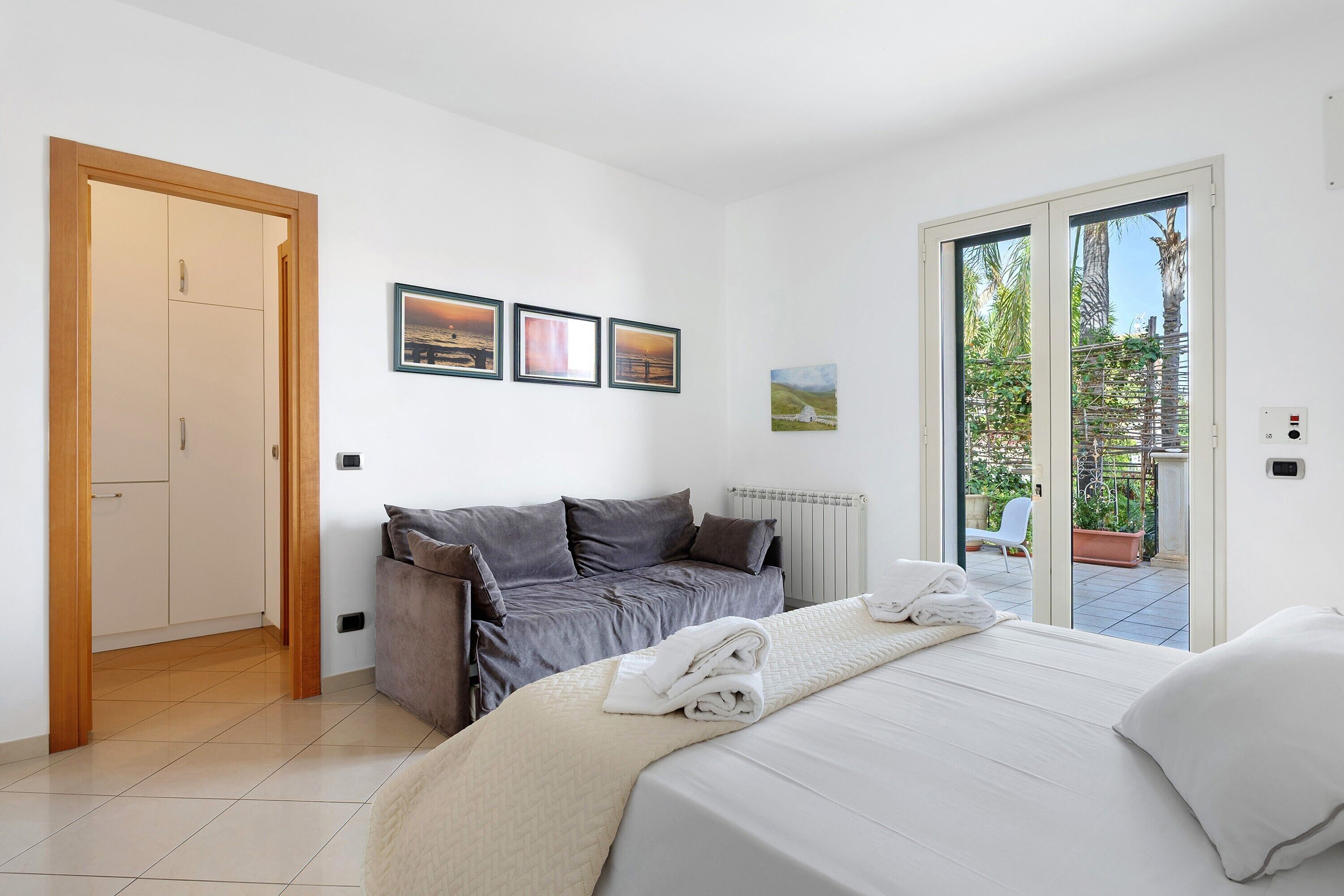 Une chambre à coucher avec un lit, un canapé, une porte et une fenêtre donnant sur un paysage verdoyant.