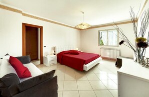 Ein Hotelzimmer mit Bett, Nachttisch, Schreibtisch, Stuhl, Heizkörper und Fenster.