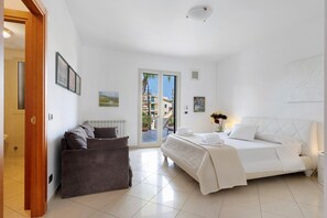 A hotel room with a bed, a sofa, a door, and a view of the outside.