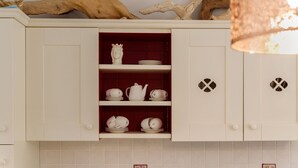 A kitchen with white cabinets, a red interior, and a decorative crown on the shelf. - Apartment 'Athena In Villa' with Shared Pool, Wi-Fi and Air Conditioning (Marina di Ragusa)