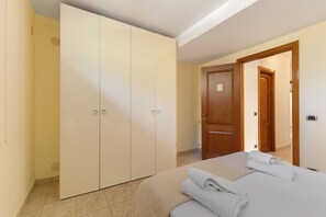 A hotel room with a bed, a wardrobe, and a door leading to another room. - Apartment 'Athena In Villa' with Shared Pool, Wi-Fi and Air Conditioning (Marina di Ragusa)