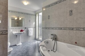 Une salle de bain avec une baignoire, un lavabo sur colonne et un miroir.