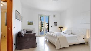 Une chambre d’hôtel avec un lit, un canapé, une porte et une vue sur l’extérieur.