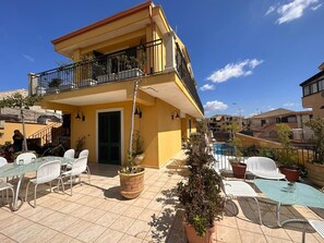Un bâtiment jaune doté d’un balcon, d’une terrasse et d’une piscine.
