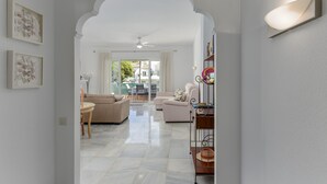 Amplia sala de estar con techo alto, ventilador de techo, sofá, una mesa de centro y una mesa de comedor con sillas.