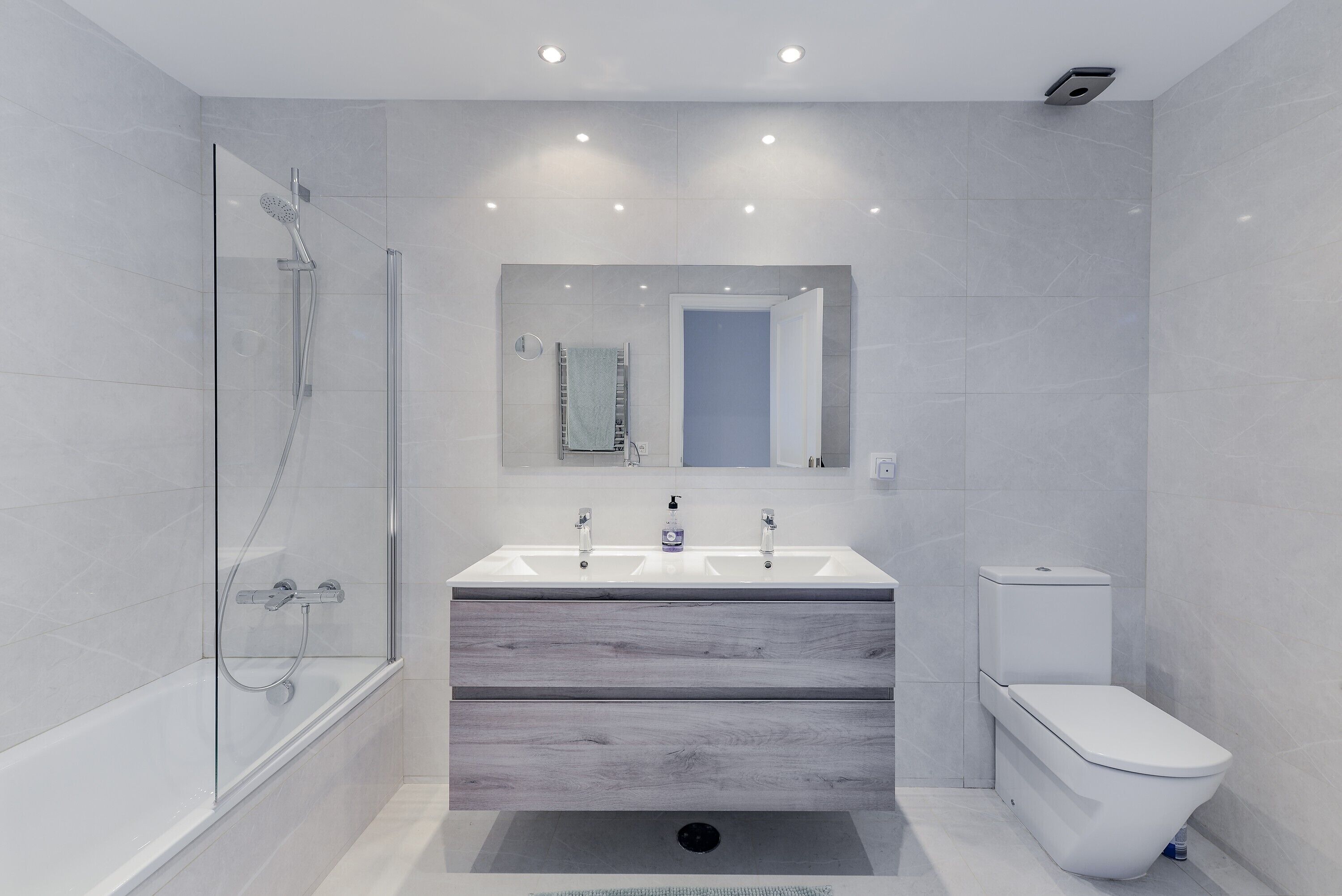 Un baño moderno con cabina de ducha de vidrio, tocador doble y un inodoro.