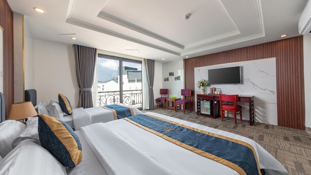 A hotel room with two beds, a desk, a TV, and a balcony with a view.