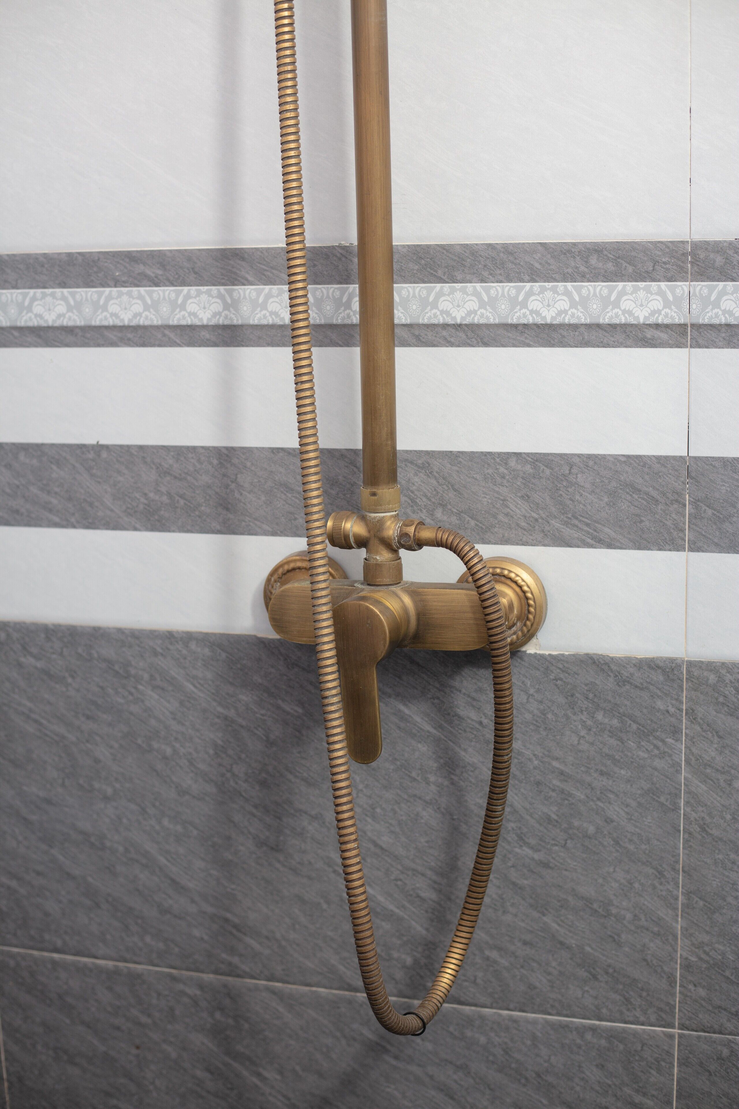 A brass showerhead with a flexible hose attached to a wall-mounted fixture.