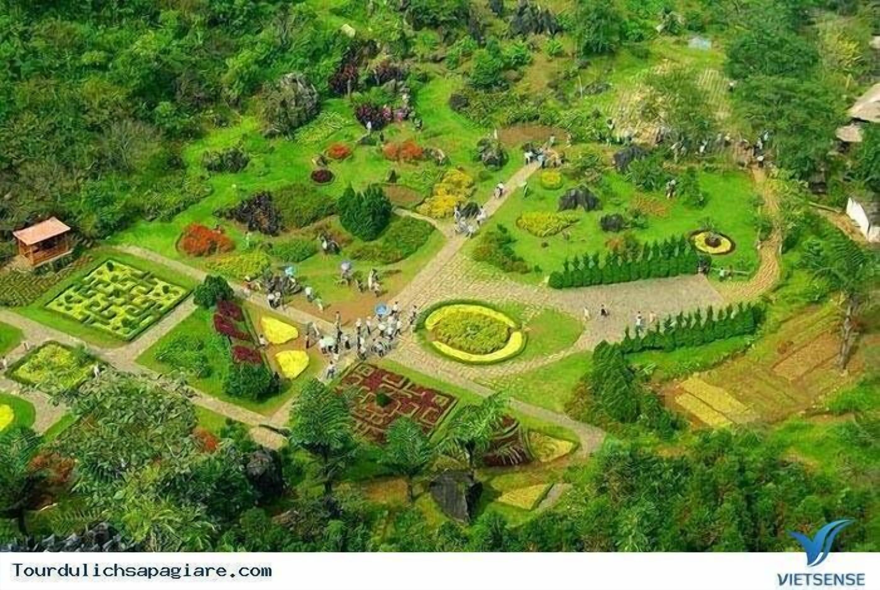 Vista aerea di un giardino con diverse composizioni floreali e un piccolo edificio.