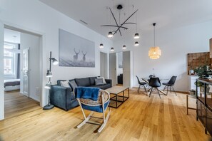 Un salon moderne comprenant un canapé, un fauteuil à bascule, une table à manger avec des chaises et un luminaire suspendu.